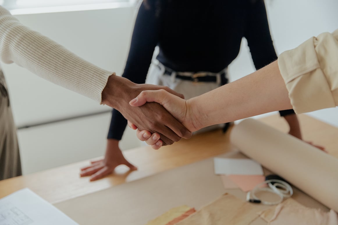 two people shaking hands over a table in an office making a deal