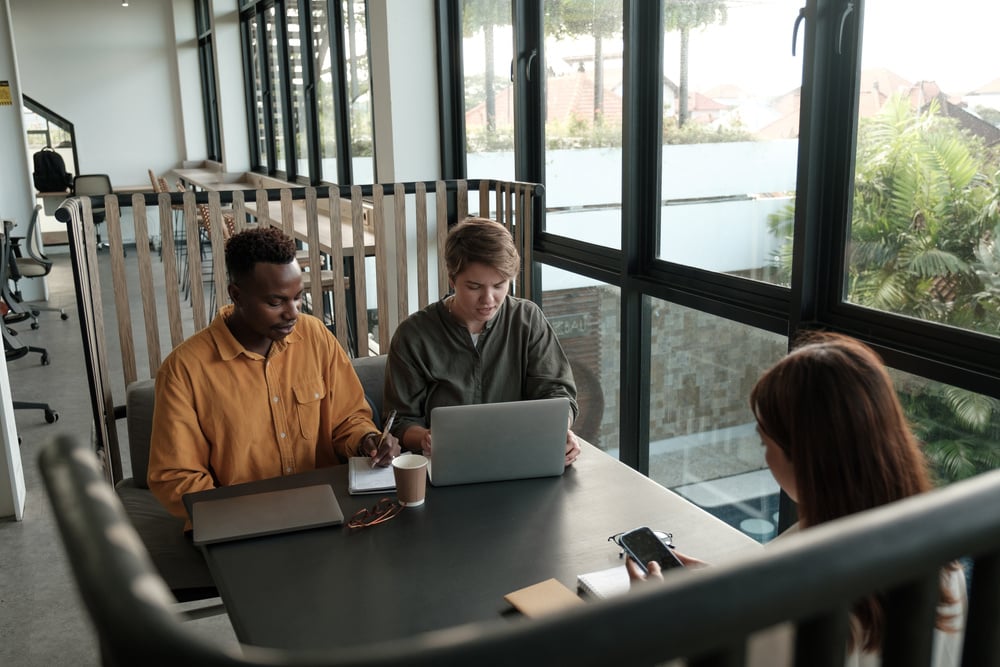 a group of diverse people collaborating at a table with laptops