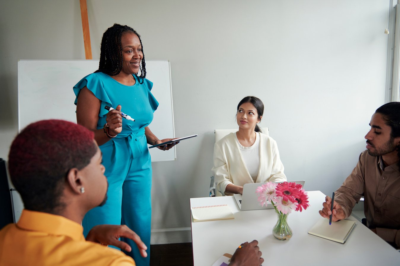 A woman is giving a presentation to a group of diverse women at a meeting.